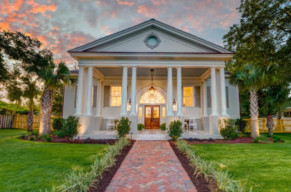 The Post Exchange at twilight: a white portico with columns, a lit lantern and a herringbone brick walk
